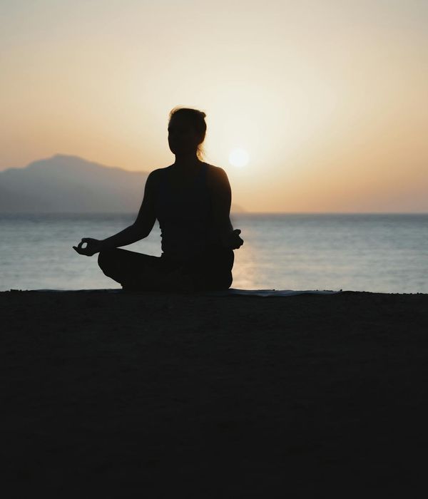 Silhouette of a woman meditating at sunset.